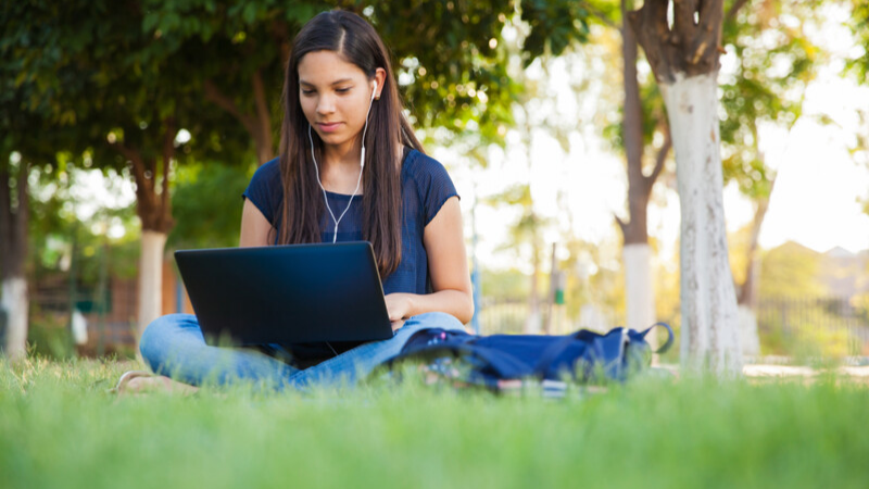 teen girl reading on her laptop outside teen girl reading on her laptop outside