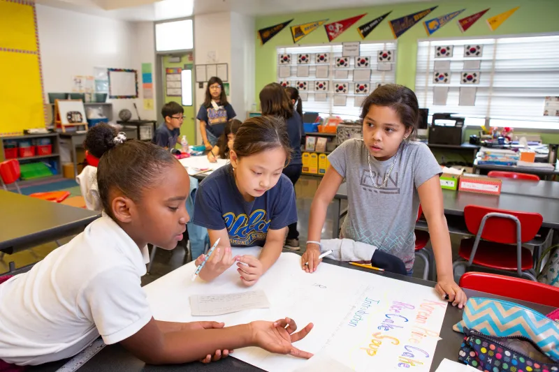 A photo of young students collaborating on a class project