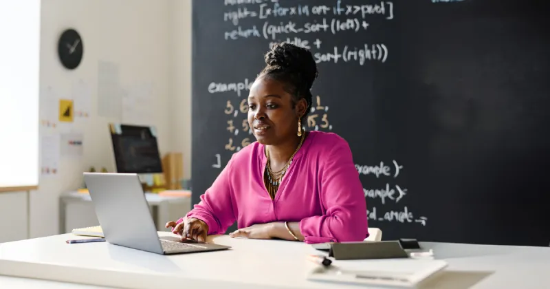 A teacher sitting at her desk, using a computer